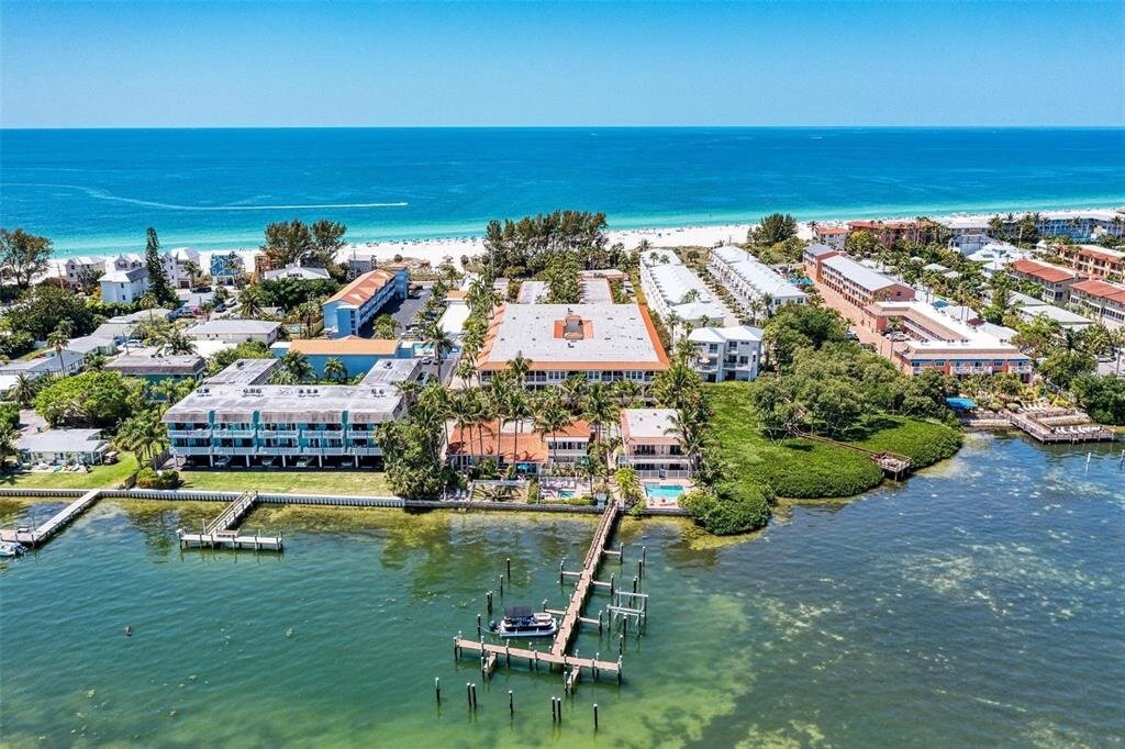 Aerial view of Tortuga Inn Beach Resort on Bradenton Beach — bay, beach, pools, and dock