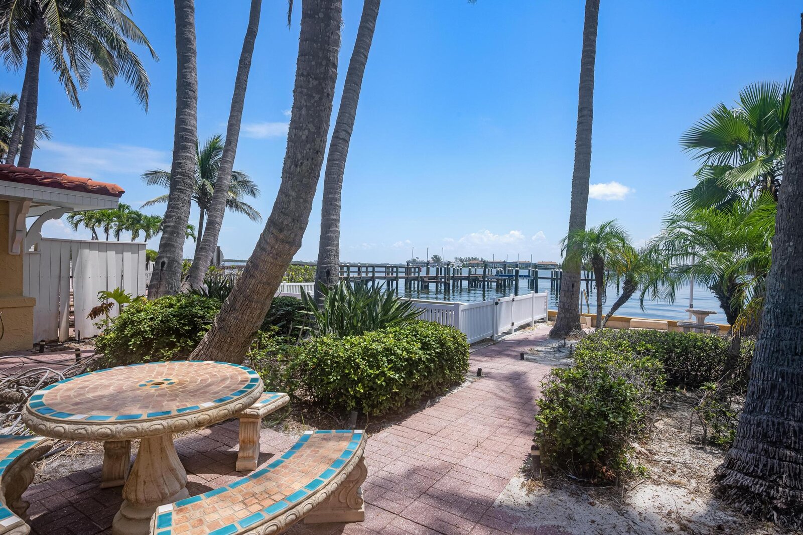 Brick patio walkway with palm trees overlooking Sarasota Bay and dock